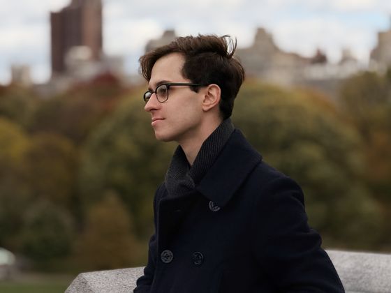 A portrait of Bradley in Central Park, New York wearing a dark blue peacoat, looking off to the left.